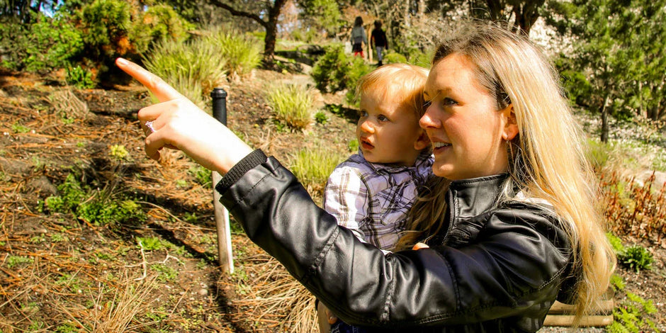 A young mother holder her child whilst looking at the wildlife
