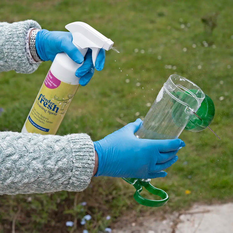 person using feeder fresh cleaning spray to clean a bird feeder