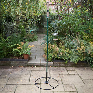 Patio base for garden pole bird feeder in a garden setting with hanging bird feeders